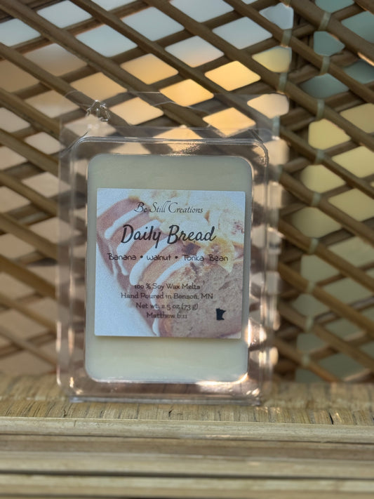 Scented wax melt with 'Daily Bread' label on a woven surface